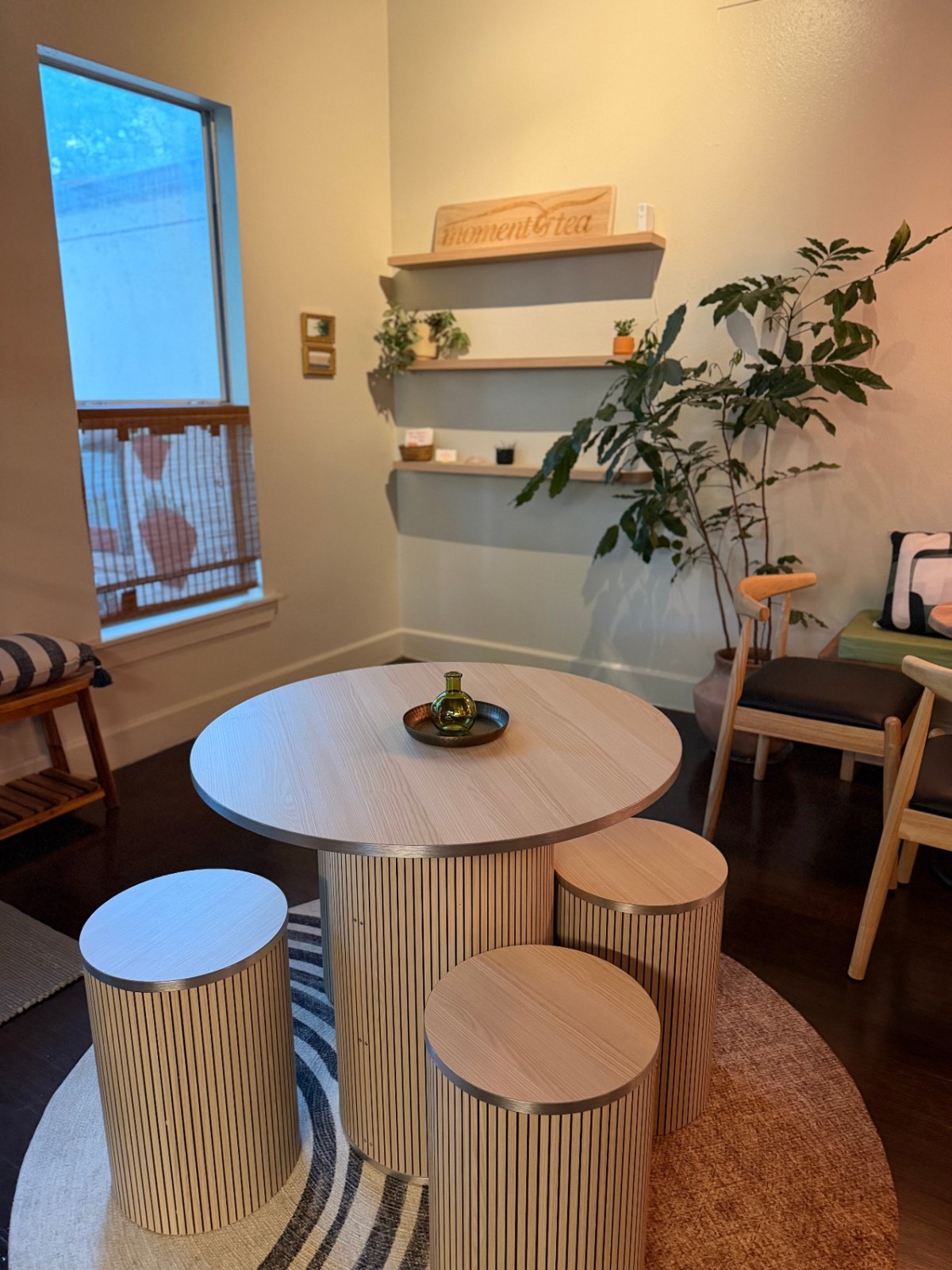 Round tea table with ribbed stools by a sunlit window
