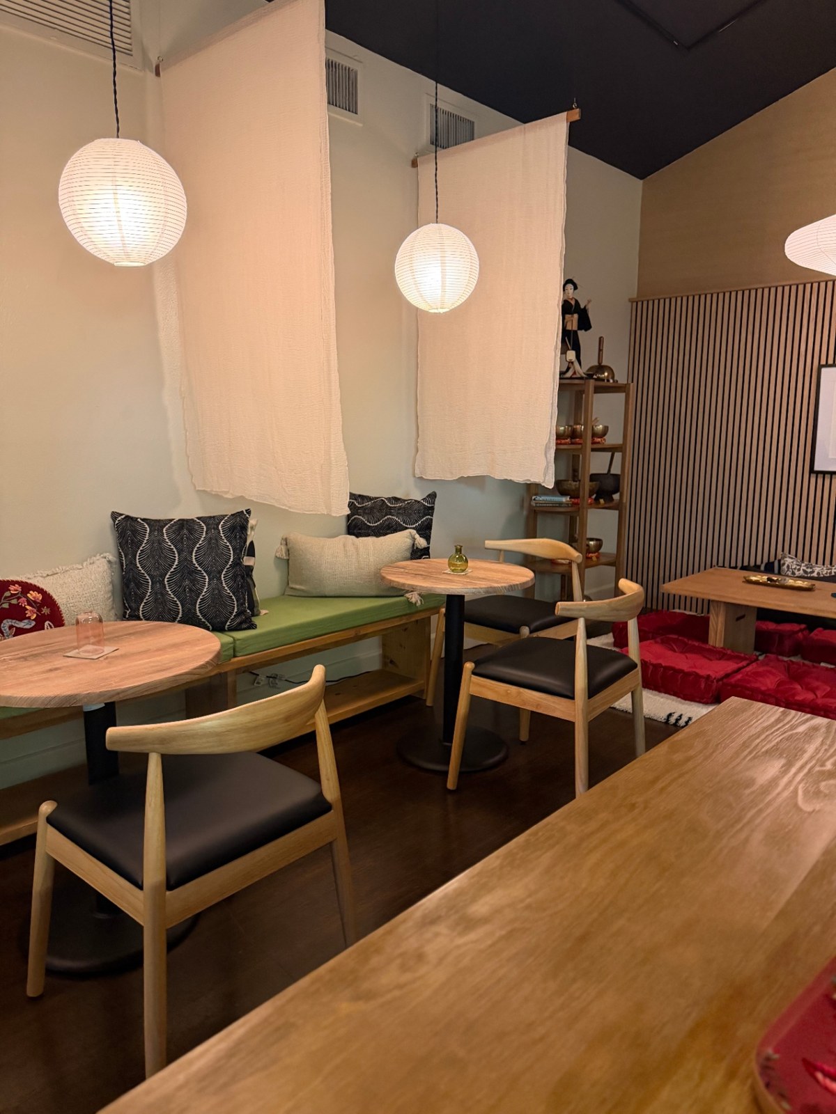 Wood tables, cedar slat wall, and hanging linen panels