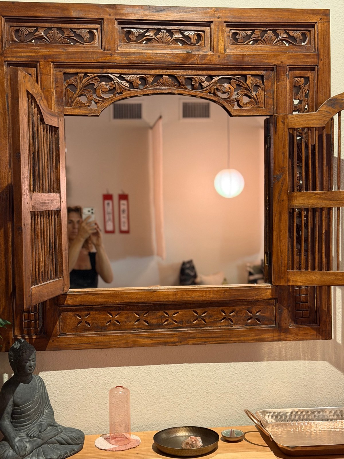 Carved teak window with Buddha and pink glass vessel